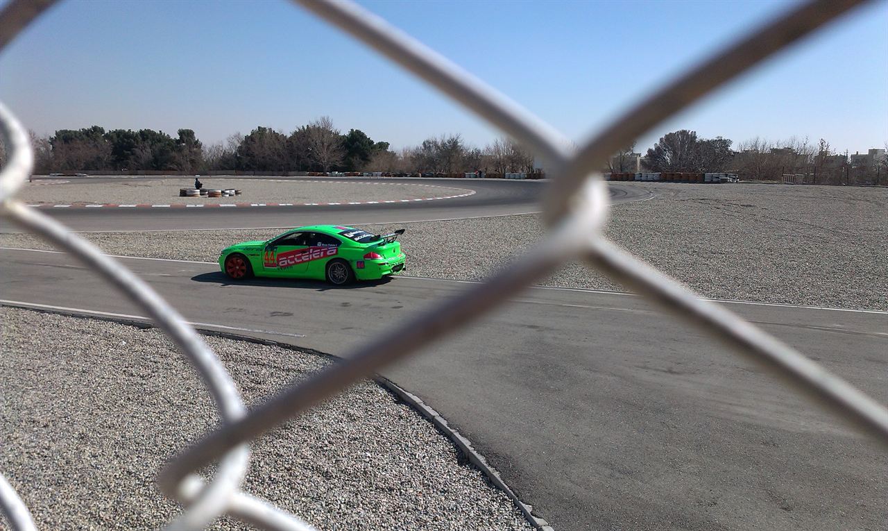 Green sports car seen through a wire fence